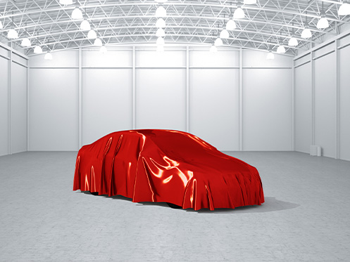 A imagem mostra um carro cobrindo por um pano vermelho em uma garagem vazia