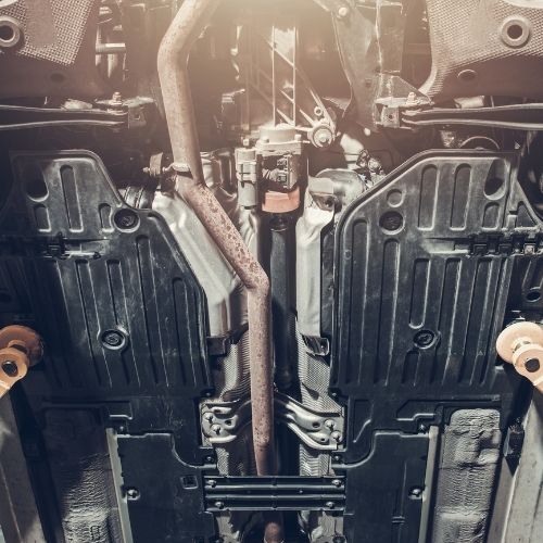 A imagem mostra o motor de um carro, com seus cilindros e pistões visíveis, montado em uma estrutura metálica, que fica conectada ao chassi do carro.