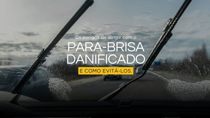 Imagem vista do interior de um carro, mostrando limpadores de para-brisa em ação em um dia nublado, com carros ao fundo na estrada, destacando segurança na condução.