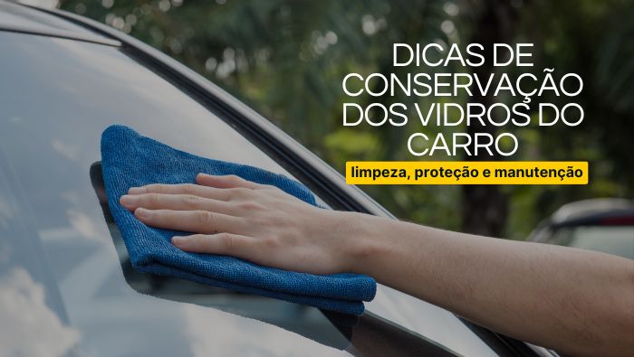 Mão limpando o para-brisa de um carro com um pano azul, refletindo o céu e as árvores ao redor, simbolizando cuidados e manutenção do veículo.